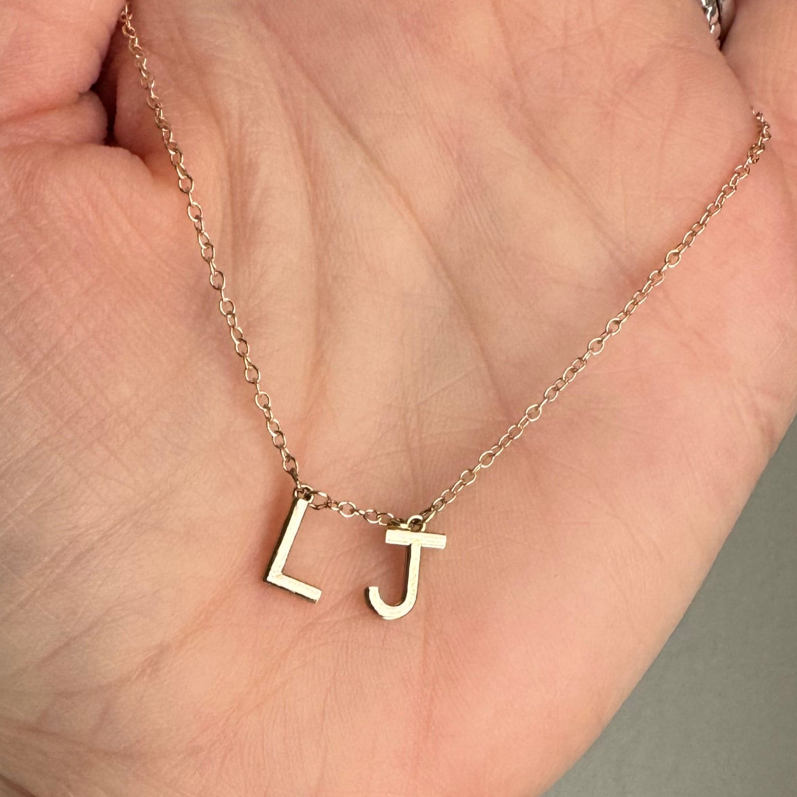 Custom 10k yellow gold initial station necklace with the initials L and J in the center of the chain. 18"