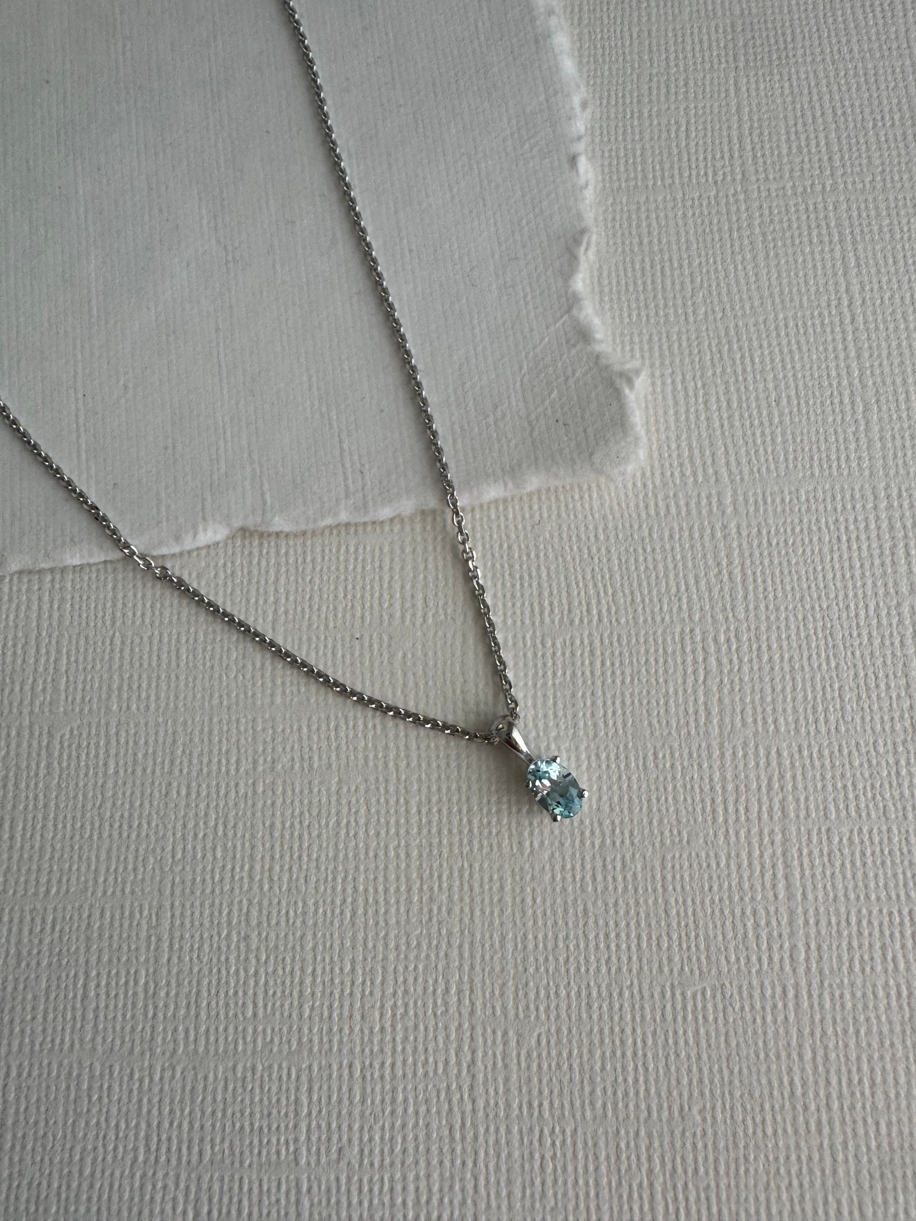 14k white gold pendant set with a 6x4mm oval natural sky blue topaz. The pendant is on a rhodium-plated, sterling silver diamond cut cable chain (1.4mm width, 18")