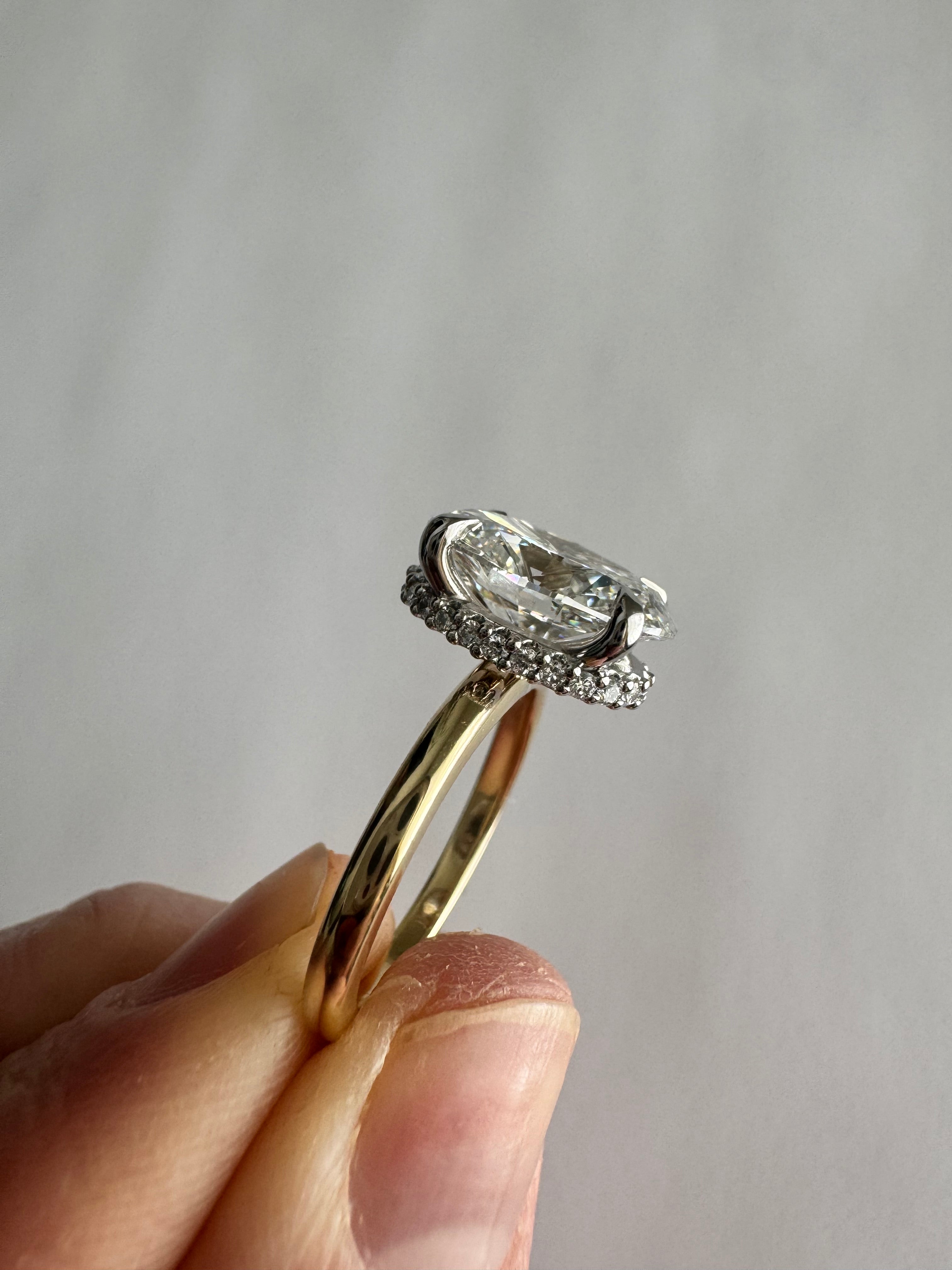 Custom, 14k yellow gold engagement ring with 14k white gold hidden halo 4 prong head. 3.03 ct lab grown oval diamond center (D, VS1). Size 5.