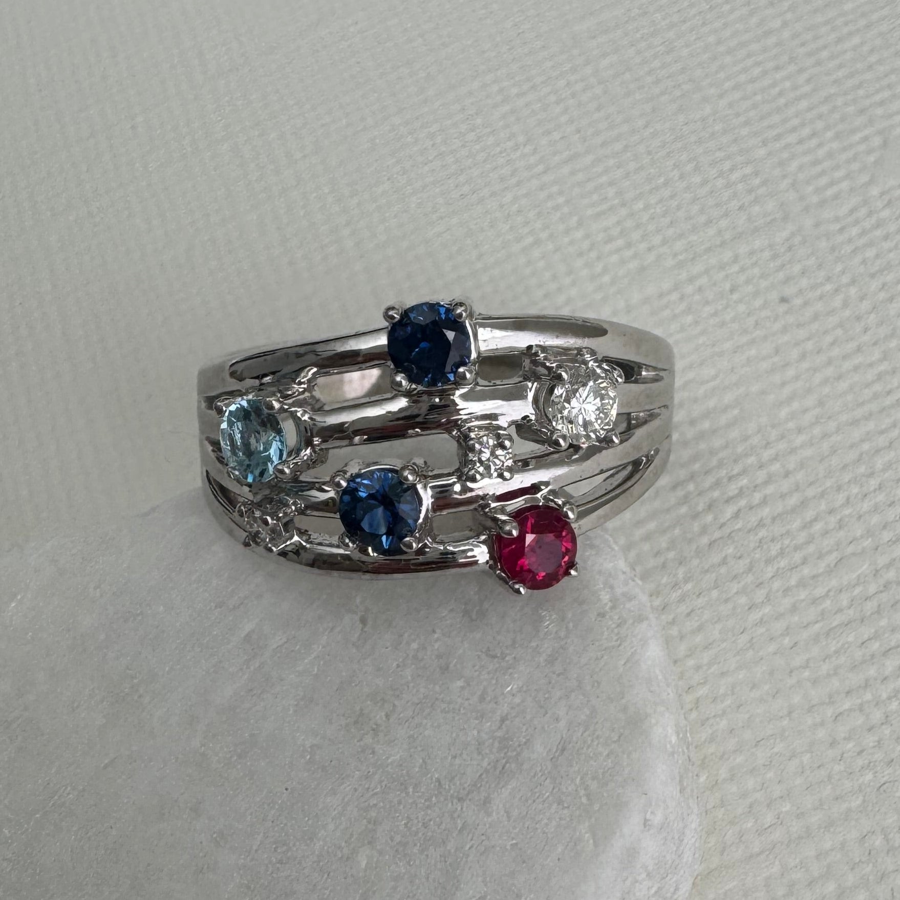 14k white gold Mother's ring with 2- 3.5 mm Round AA Blue Sapphire, 1- 3.5mm round AA ruby, 1- 3.5 mm Round AA Aquamarine, 1- 3.4 mm Round Diamond, 2- 1.8mm round diamonds. Size 10.