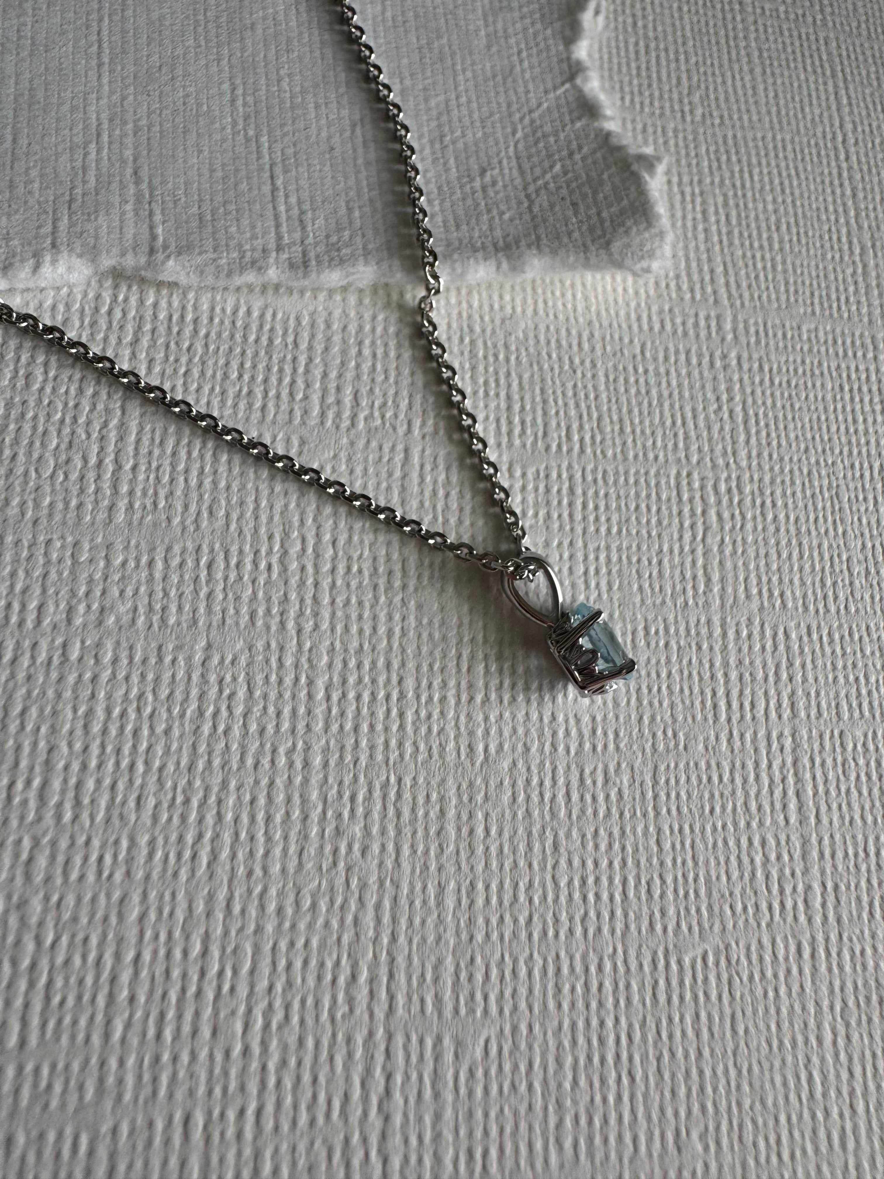 14k white gold pendant set with a 6x4mm oval natural sky blue topaz. The pendant is on a rhodium-plated, sterling silver diamond cut cable chain (1.4mm width, 18")
